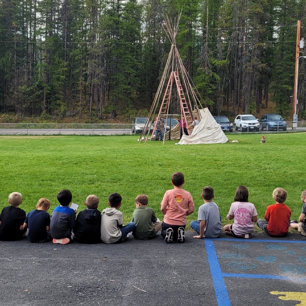 students watching a teepee being set up